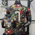 Front and back views of a black Bayern Munich short-sleeve jersey with a multicolored abstract design, cream Gnabry number 7 print and Telekom sponsor, alongside UCL and Bundesliga graphics.