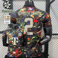  Front and back views of a black Bayern Munich short-sleeve jersey with a multicolored abstract design, cream Upamecano number 2 print and Telekom sponsor, alongside UCL and Bundesliga graphics.