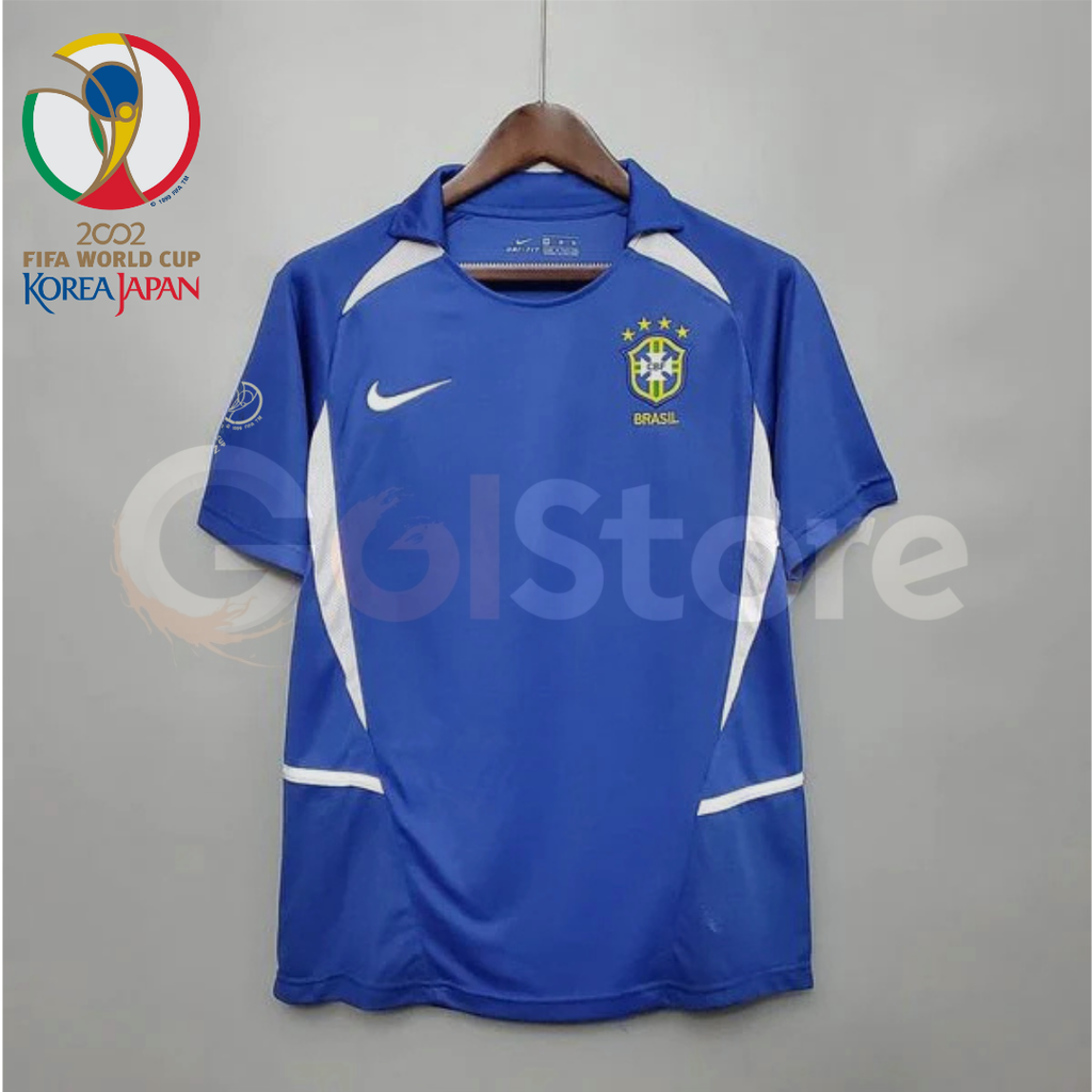  Front view of a blue Brazil 2002 retro short-sleeve away jersey with white shoulder and side panels, Brazil crest and a sleeve patch.