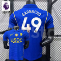 Front and back views of a blue Chelsea short-sleeve jersey with yellow details, white Garnacho number 49 print and a gold chest badge, alongside a Premier League graphic.
