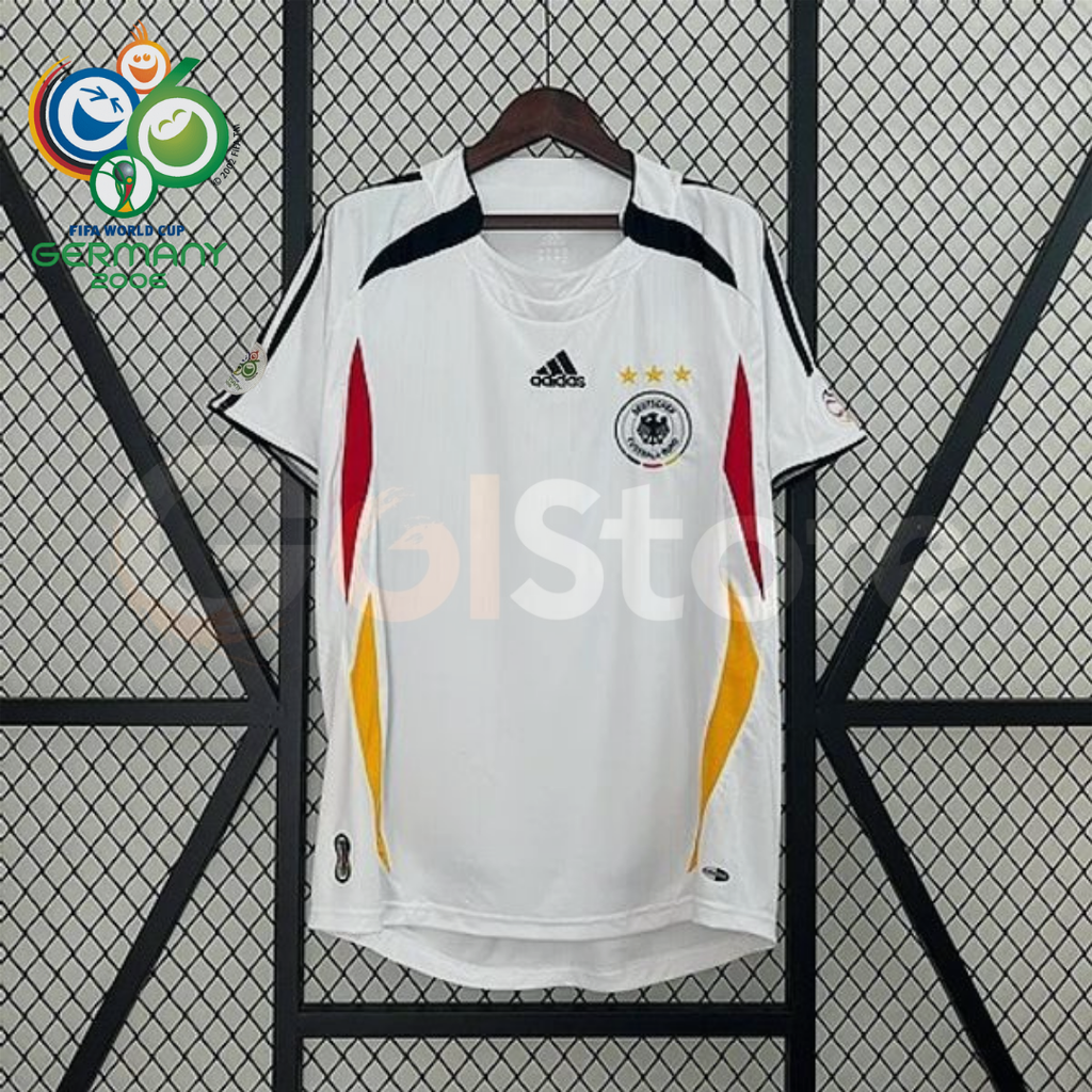 Front view of a white Germany 2006 retro short-sleeve home jersey with black shoulder details, red and gold side panels, and the German football crest.