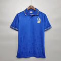 Front view of a blue Italy short-sleeve retro home jersey with a polo collar, subtle tonal pattern, Italian tricolour detailing on the collar and cuffs, and an Italy crest.