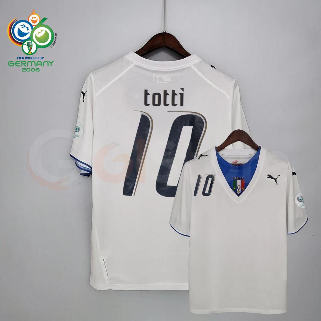 Front and back views of a white Italy short-sleeve retro away jersey with a blue neckline panel, dark Totti number 10 print and sleeve patches, alongside a Germany 2006 World Cup graphic.
