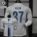 Front and back views of a white Manchester City long-sleeve jersey with blue central stripes, blue Allan number 37 print and Etihad Airways sponsor, alongside UCL graphics.