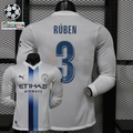  Front and back views of a white Manchester City long-sleeve jersey with blue central stripes, blue Rúben number 3 print and Etihad Airways sponsor, alongside UCL graphics.