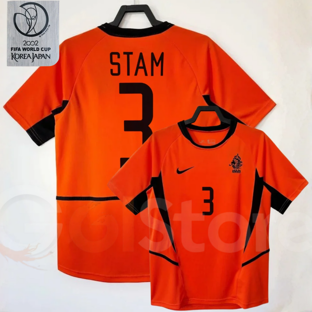 Netherlands orange short-sleeve retro jersey, front and back views with STAM 3 print, black collar and side panels, alongside a 2002 World Cup graphic.
