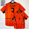 Netherlands orange short-sleeve retro jersey, front and back views with STAM 3 print, black collar and side panels, alongside a 2002 World Cup graphic.
