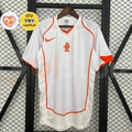 Front view of a white Netherlands 2004 away retro short-sleeve jersey with orange piping, an orange crest and Nike logo, alongside EURO and UEFA Fair Play graphics.