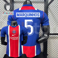 Front and back views of a blue PSG short-sleeve jersey with a red and white central stripe, Marquinhos lettering and white number 5, alongside trophy and UEFA Foundation graphics.