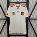 Spain white short-sleeve retro jersey with red and yellow shoulder stripes, a V-neck collar, Spain crest with a gold star and a gold FIFA World Champions chest badge.
